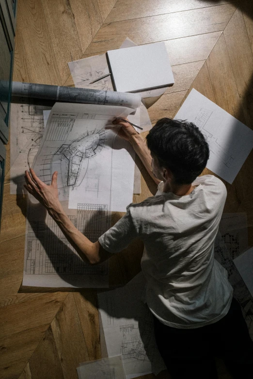 a man sitting on top of a hard wood floor, a drawing, pexels contest winner, arbeitsrat für kunst, architectural plan, lit from above, woman, storyboarding
