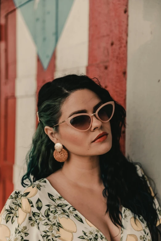 a woman wearing sunglasses leaning against a wall, by Winona Nelson, pexels contest winner, rockabilly hair, latinas, vintage muted colors, wearing ornate earrings