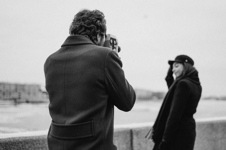 a black and white photo of a man taking a picture of a woman, a black and white photo, by Emma Andijewska, high quality upload, low detail, medium format, portrait”