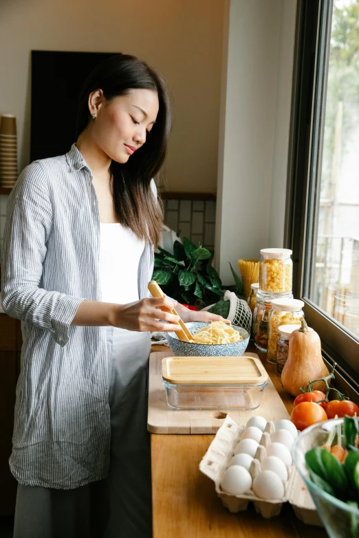 a woman standing in a kitchen preparing food, pexels contest winner, happening, mac and cheese, young asian woman, pregnancy, square