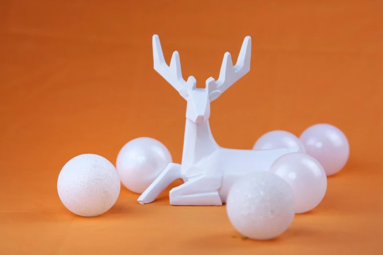 a white sculpture of a deer surrounded by balls, inspired by Rudolph F. Ingerle, pexels contest winner, plasticien, tabletop model, white and orange, minimalist, pearlescent