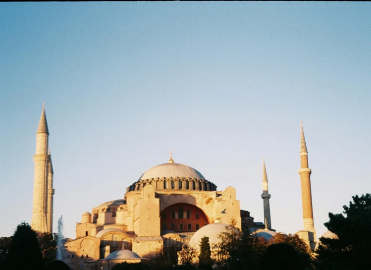 a group of people standing in front of a building, a colorized photo, pexels contest winner, hurufiyya, domes, afternoon sun, byzantine, photo taken on fujifilm superia