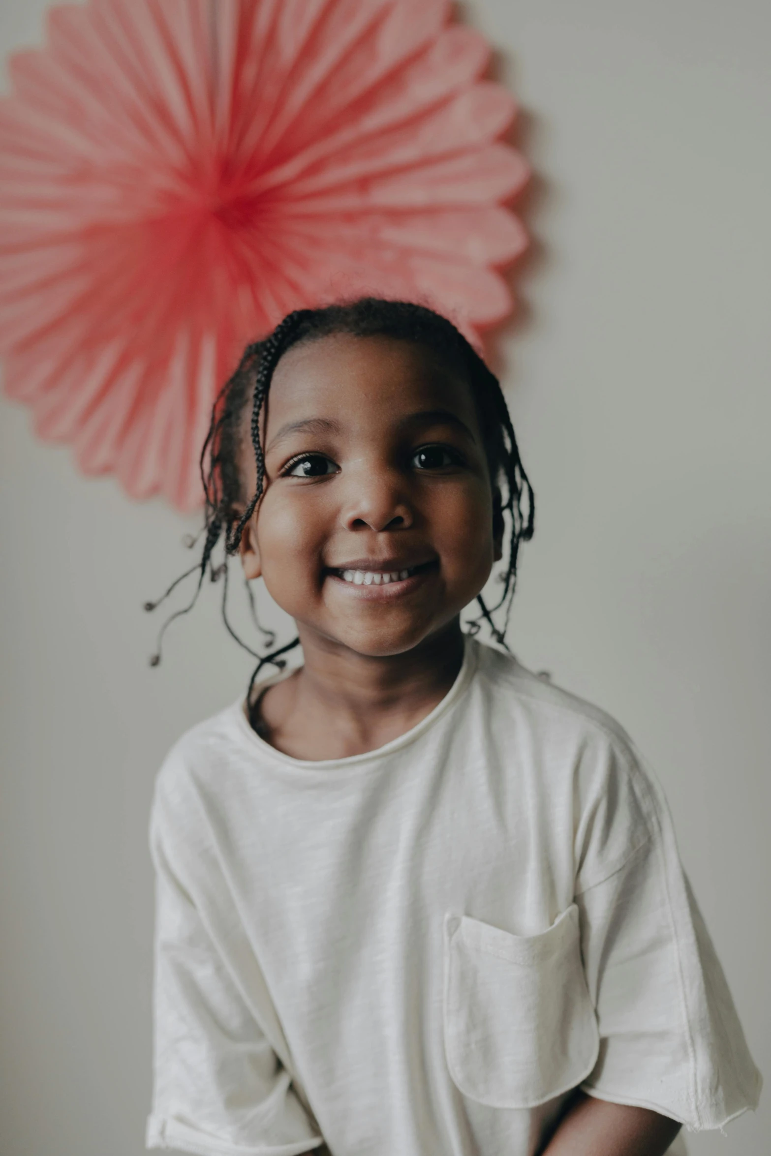 a little girl standing in front of a pink fan, pexels contest winner, brown skinned, smiling and looking directly, young boy, an all white human