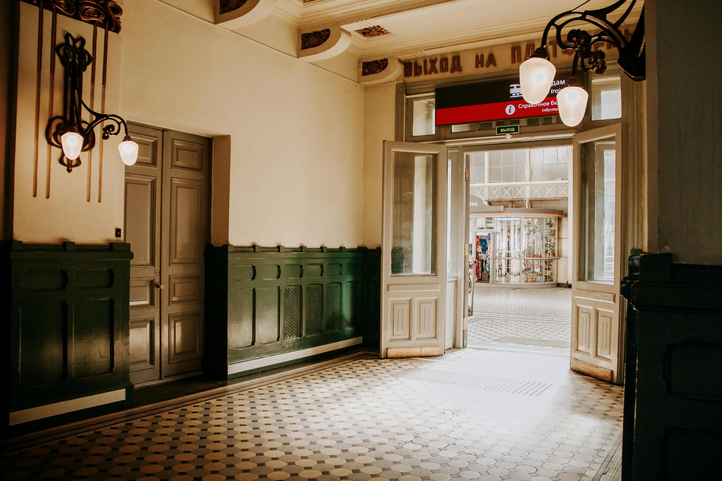 a hallway in a building with a chandelier hanging from the ceiling, a photo, pexels contest winner, art nouveau, budapest street background, wes anderson background, exiting store, olive green and venetian red