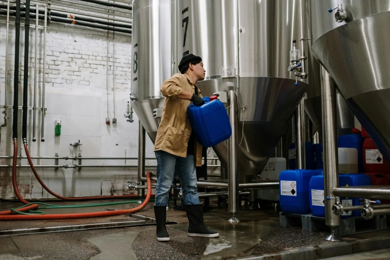 a man standing in front of a bunch of tanks, a photo, by Julia Pishtar, pexels contest winner, process art, beer, working, non-binary, winter