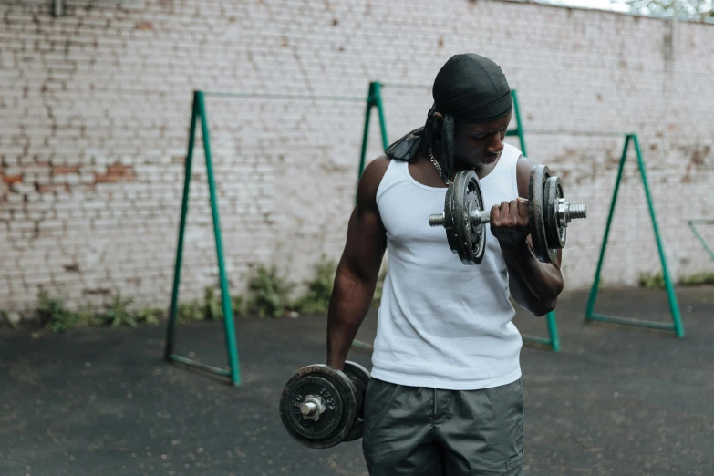 a man holding two dumbbells in a parking lot, pexels contest winner, dark-skinned, working out in the field, wearing a vest top, pistons and bolts