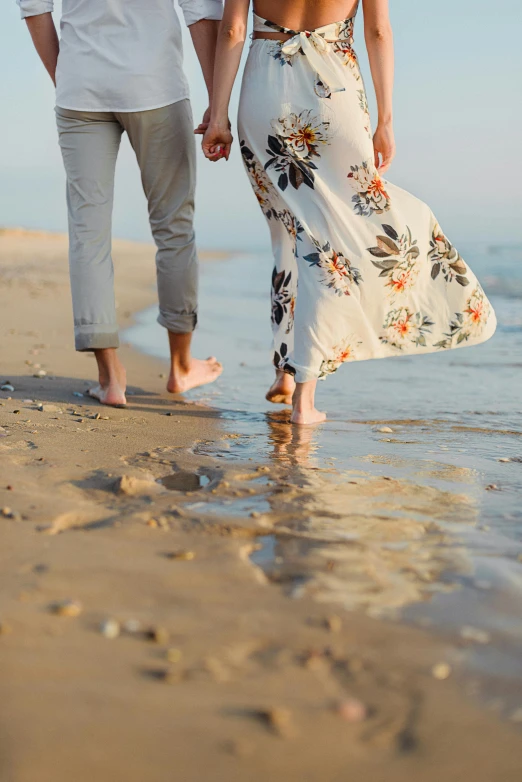 a man and woman walking on the beach holding hands, unsplash, renaissance, elegant feet, wearing a flowing sundress, rhode island, feet in water