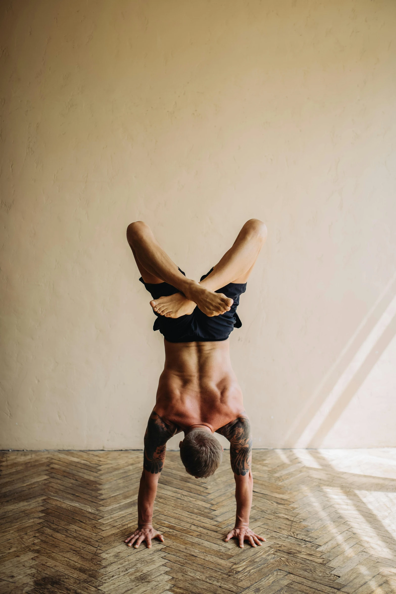 a man doing a handstand in a room, trending on pexels, arabesque, lean man with light tan skin, tattooed, yoga, top down