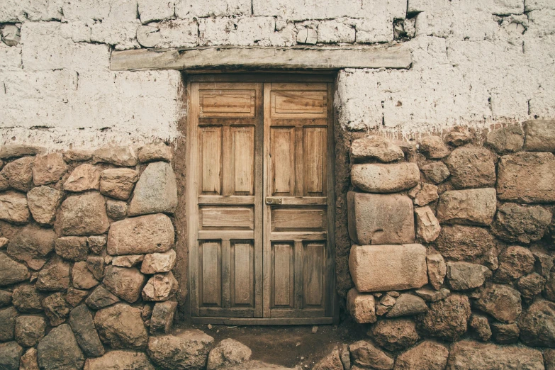 an old stone building with a wooden door, an album cover, by Elsa Bleda, unsplash, andes, 1900s photo, tourist photo, background image