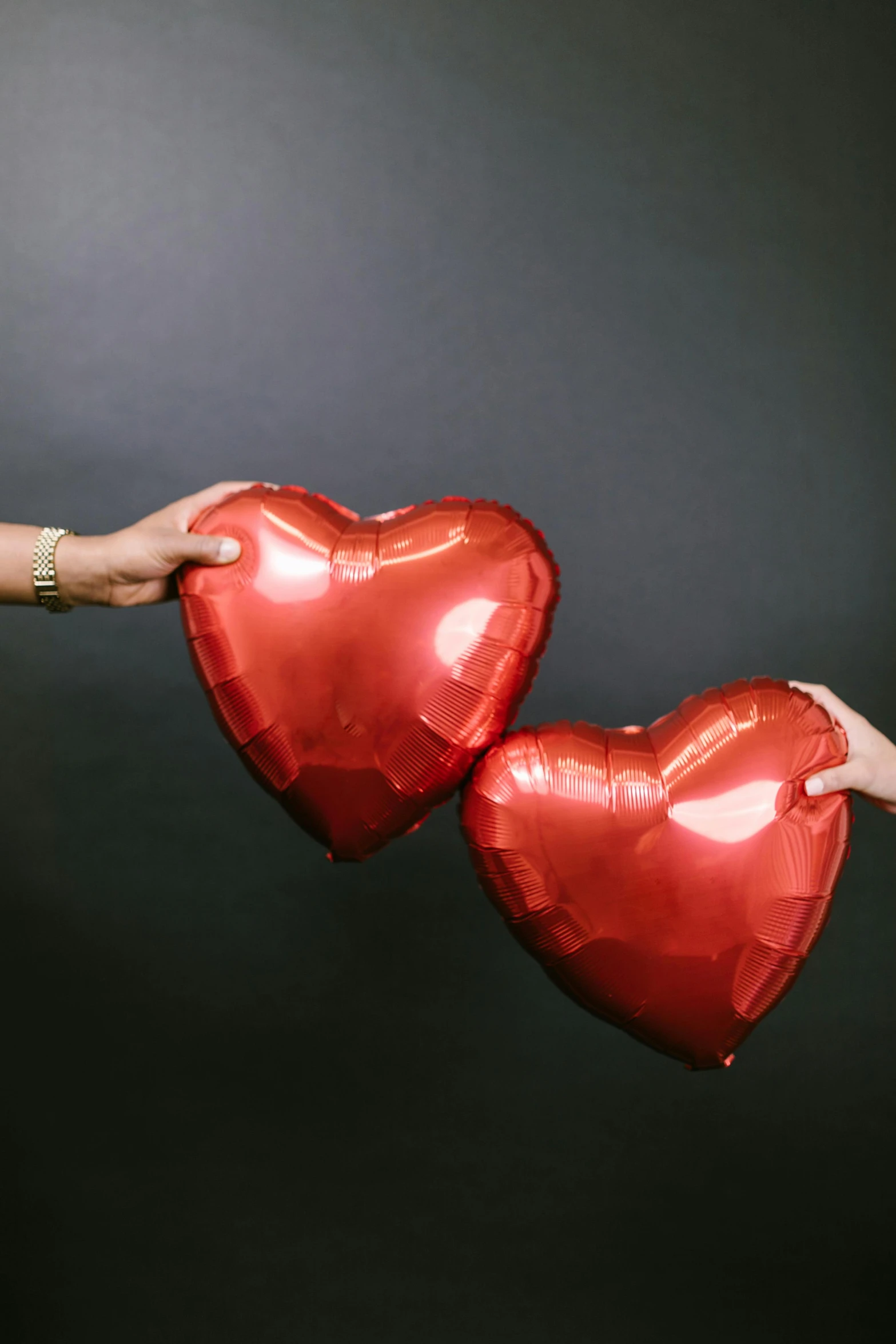 a woman holding two red heart shaped balloons, pexels, 240p, metallic red, holding each other hands, ✨🕌🌙