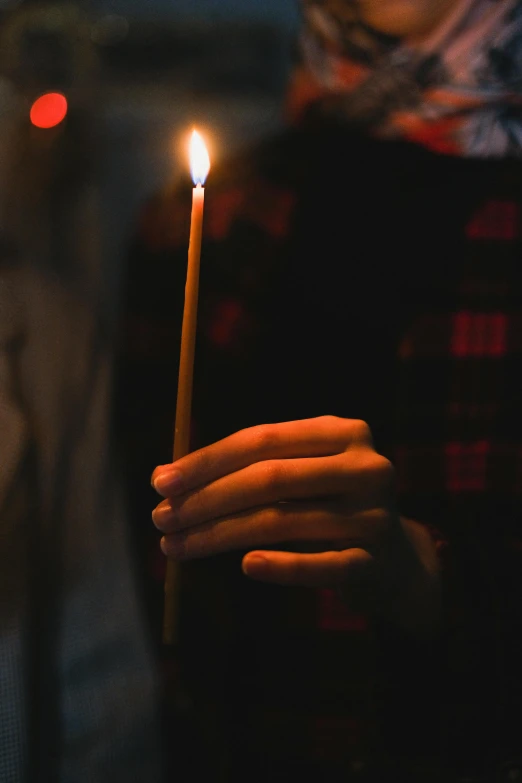 a person holding a lit candle in their hand, holding a wooden staff, profile image