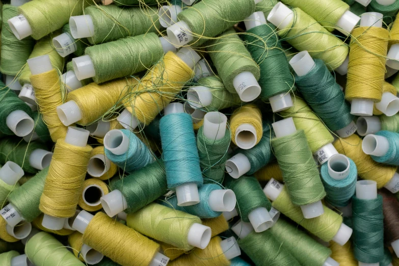 a pile of spools of thread sitting on top of each other, unsplash, arts and crafts movement, green and yellow, medium, silk, greenery