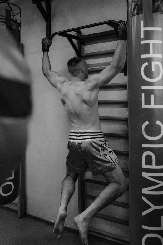 a man standing in front of a punching bag, a black and white photo, inspired by Ludovit Fulla, reddit, happening, his back is turned, фото девушка курит, 30 year old man :: athletic, candid photo