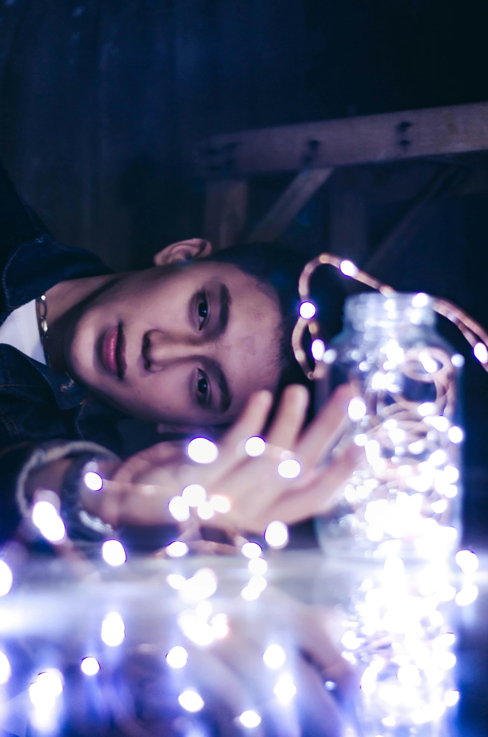 a man laying on top of a bed covered in christmas lights, a portrait, inspired by Elsa Bleda, unsplash, cai xukun, non binary model, person made out of glass, sad look