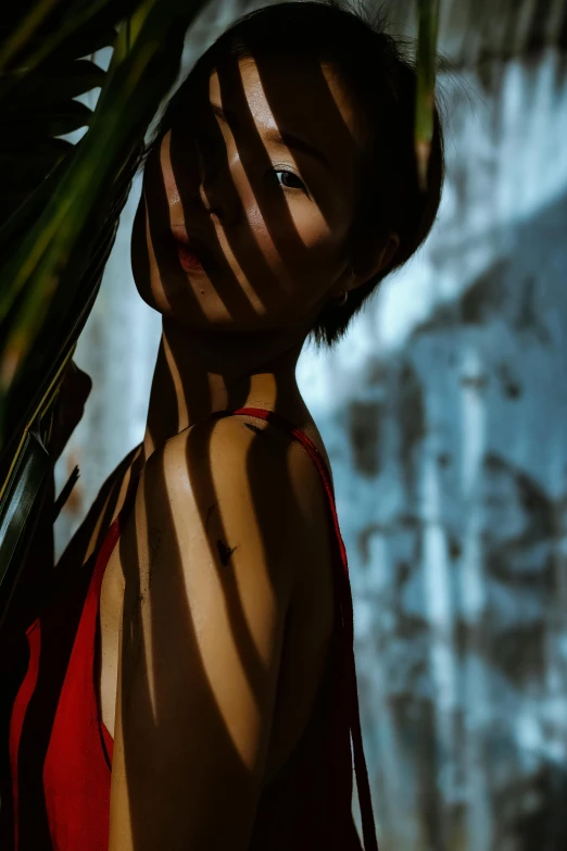 a woman in a red bikini standing in front of a waterfall, inspired by Ren Hang, featured on cgsociety, faces covered in shadows, chest covered with palm leaves, shot at dark with studio lights, stripes