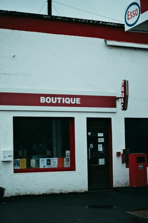 a red and white building with a sign that says boutique, an album cover, unsplash, postage, 1990s photograph, convenience store, small library