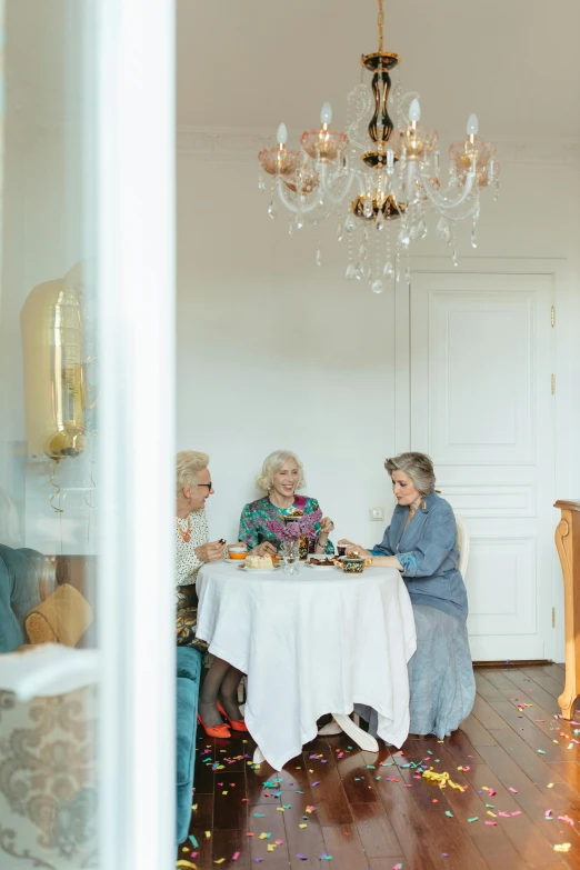 a couple of people that are sitting at a table, by Zofia Stryjenska, unsplash, rococo, three women, in a white room, elderly, conde nast traveler photo