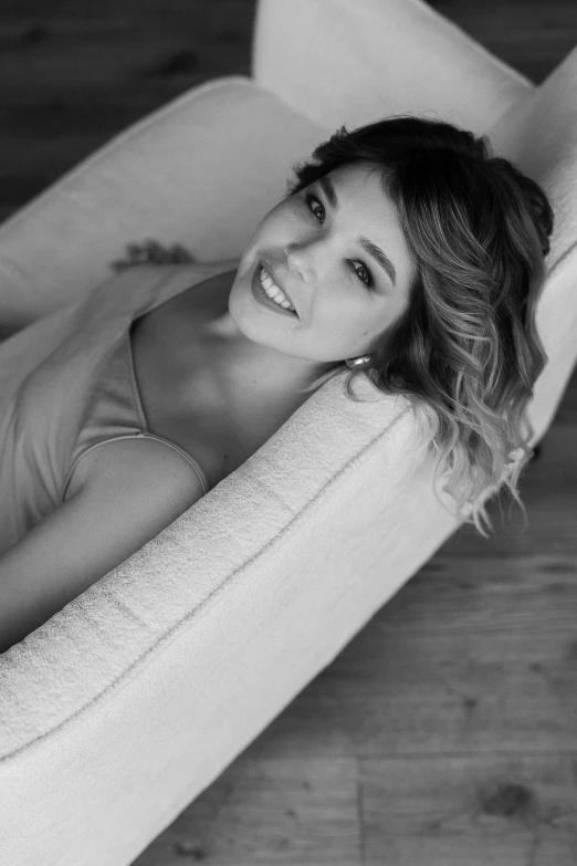 a black and white photo of a woman laying on a couch, by Niyazi Selimoglu, with a beautifull smile, sofya emelenko, happy and beautiful, evening time