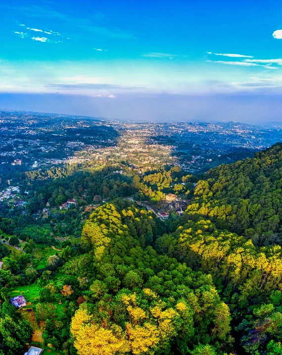 a view of a city from the top of a hill, pexels contest winner, sumatraism, lush forest in valley below, aerial, full colour, panoramic