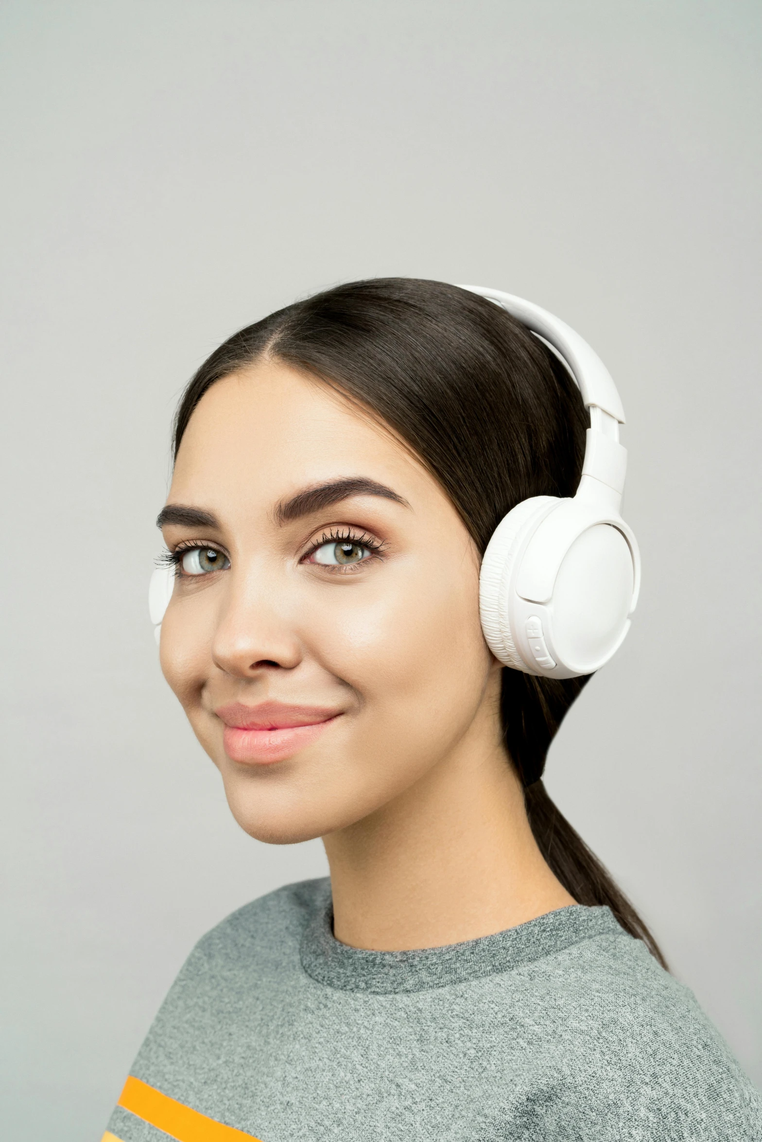 a woman wearing headphones and smiling at the camera, trending on pexels, renaissance, on a gray background, detailed product image, with a white, half turned around