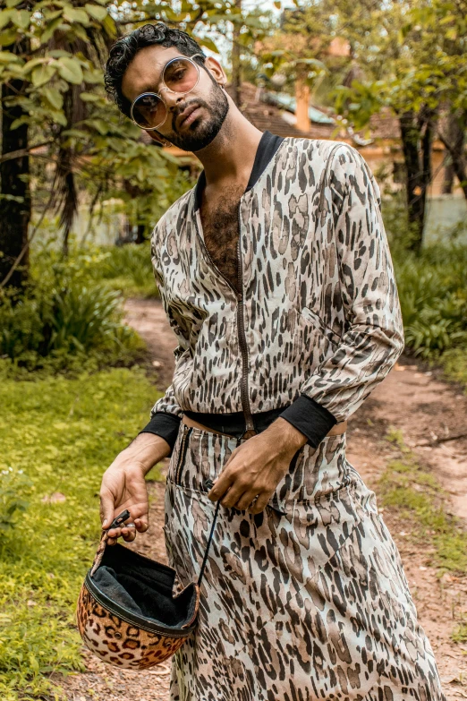 a man standing on a dirt road holding a purse, by Nina Hamnett, trending on pexels, renaissance, wearing disco suit, humanoid cheetah, in sao paulo, male model