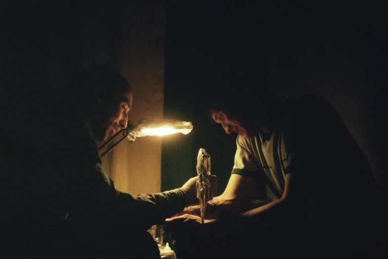 two men sitting next to each other in a dark room, by Elsa Bleda, hyperrealism, casting a flame spell, puppets, 1980s photograph, in a workshop