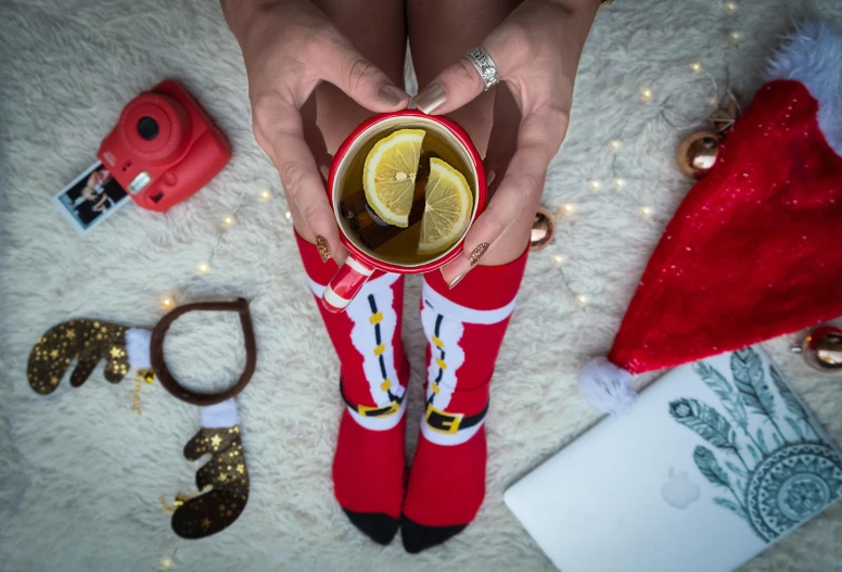 a close up of a person holding a cup of tea, sitting on santa, overknee socks, wearing a lemon, flatlay