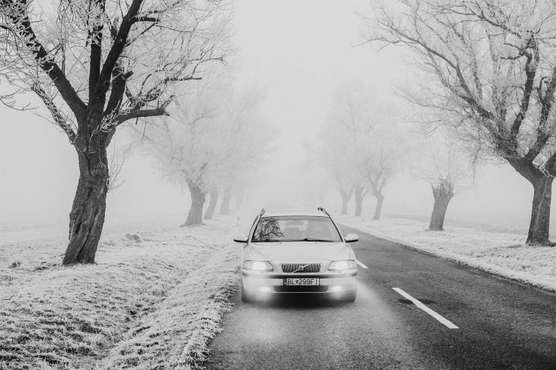 a car driving down a snow covered road, a black and white photo, by Kristian Zahrtmann, pexels contest winner, romanticism, white fog painting, (3 are winter, tourist photo, white witch