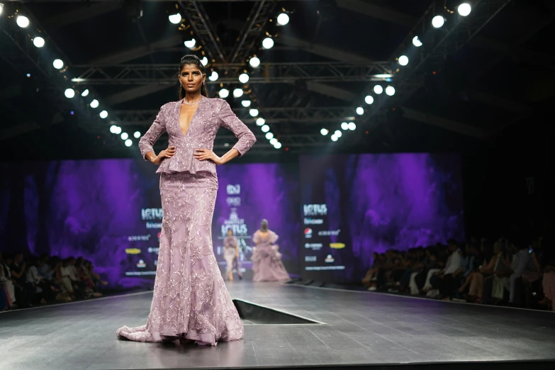 a woman in a purple dress on a runway, kitsch movement, platinum jewellery, thumbnail, vastayan, in the evening