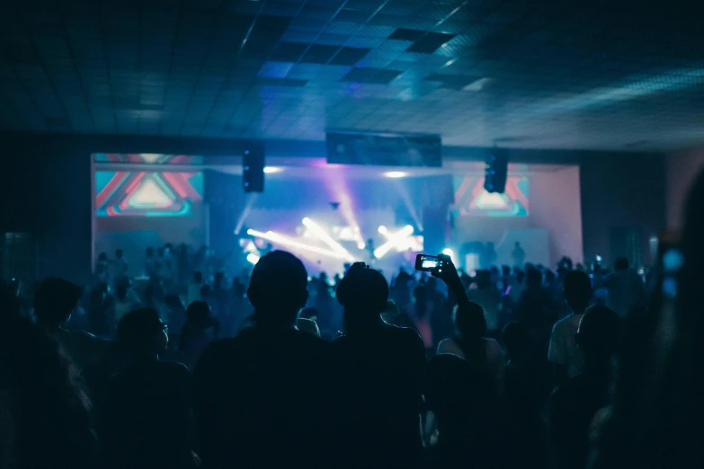 a group of people standing in front of a stage, unsplash, happening, club lighting, standing inside of a church, from the distance, photograph of three ravers