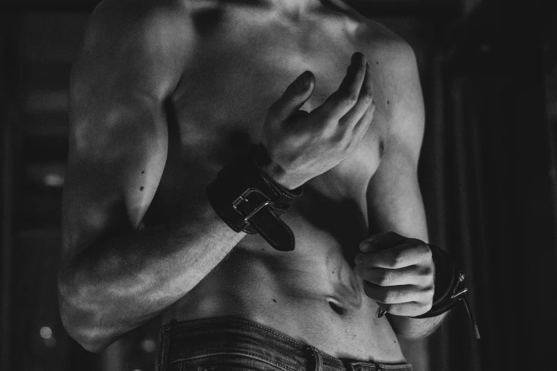 a black and white photo of a shirtless man, a black and white photo, by Emma Andijewska, pexels, renaissance, leather cuffs around wrists, flirting, ilustration, handcuffed