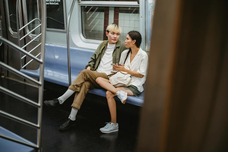 a couple of people sitting next to each other on a train, pexels contest winner, nonbinary model, in new york city, casual modern clothing, muted colors. ue 5
