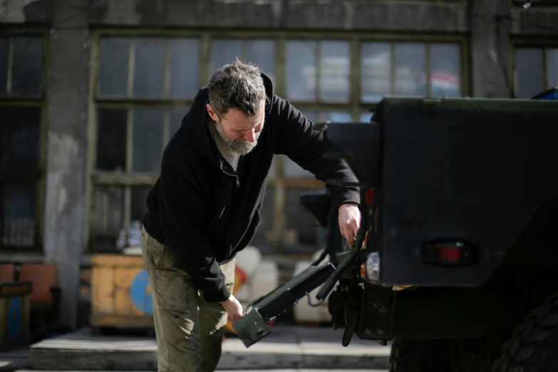 a man putting something in the back of a truck, by Haukur Halldórsson, pexels contest winner, auto-destructive art, aged armor plating, petrol, olafur eliasson, from the elbow