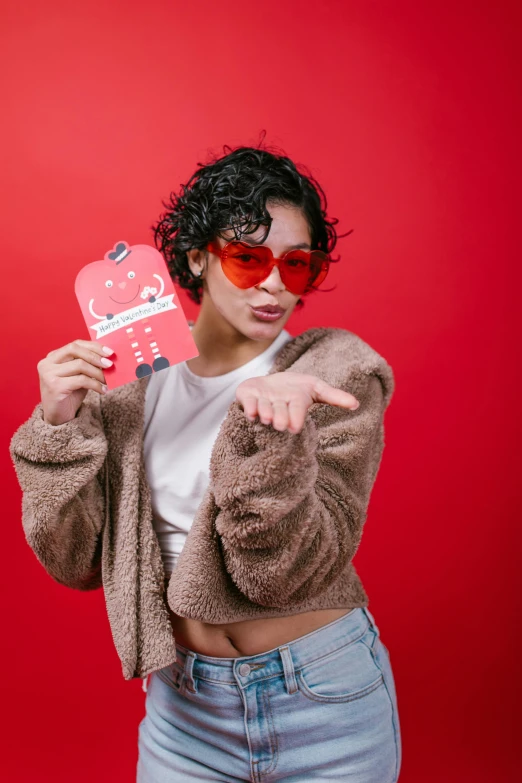 a woman standing in front of a red wall holding a heart, an album cover, trending on pexels, pop art, ( bear wearing sunglasses, holding ace card, an asian woman, ox