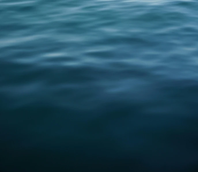 a person riding a surf board on top of a body of water, inspired by Elsa Bleda, unsplash, minimalism, dark blue, blurry, ignant, abstract photography