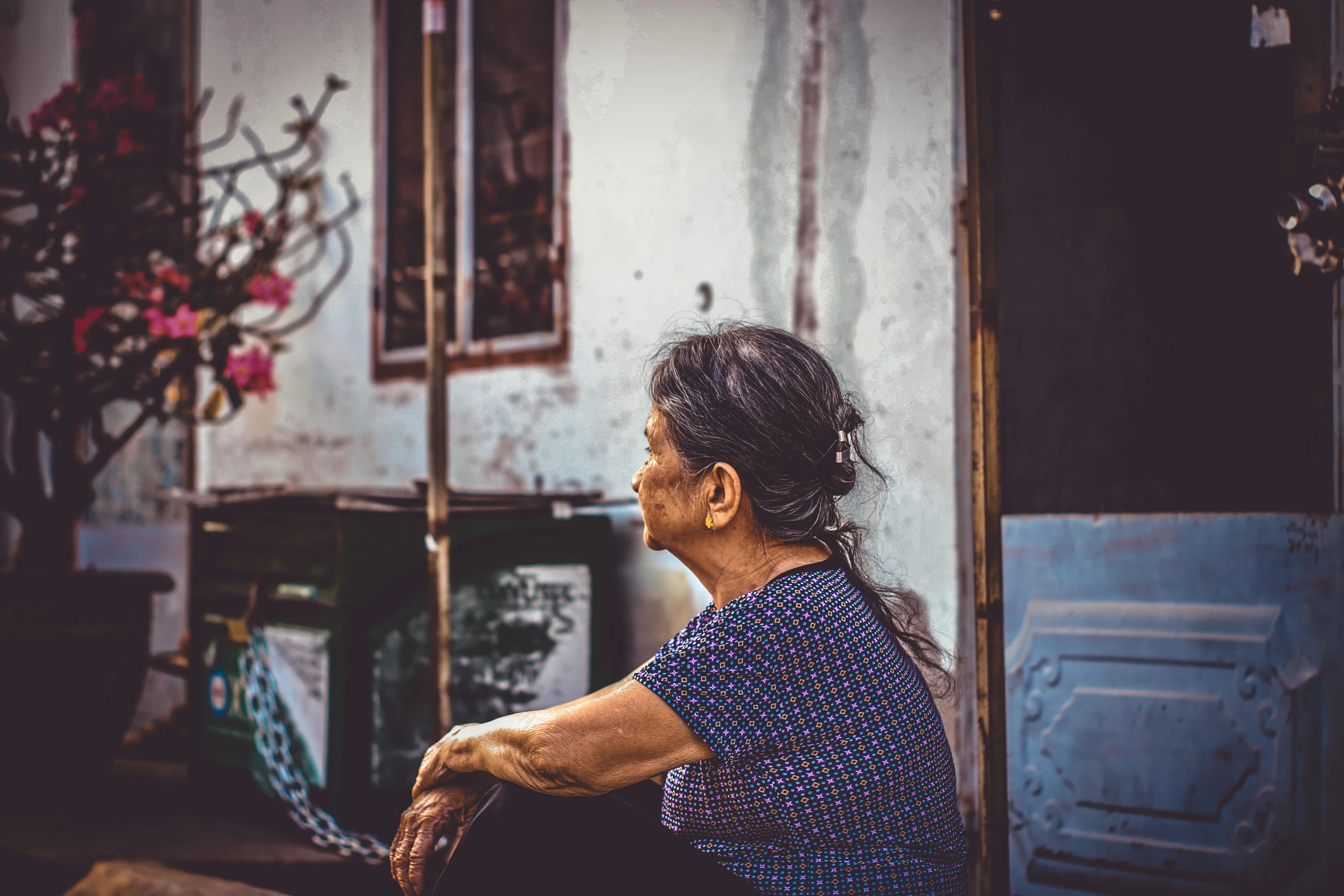 a woman sitting on a bench in front of a building, pexels contest winner, looking old, vietnam, profile image, grungy