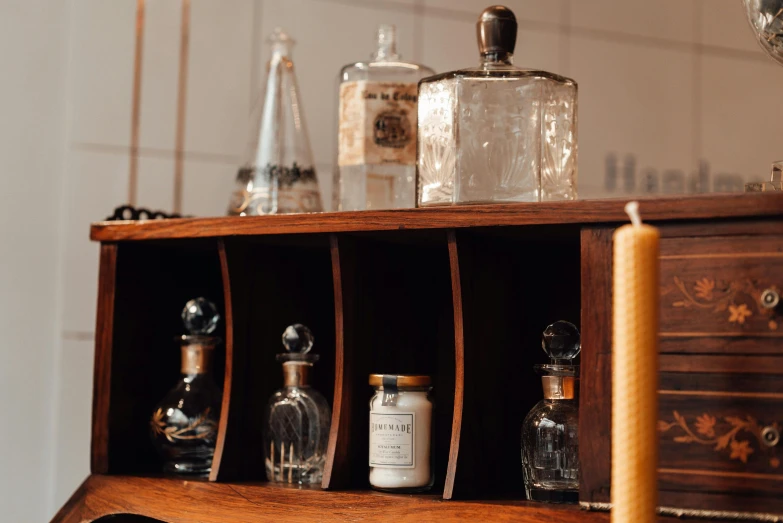 a wooden cabinet with bottles on top of it, a still life, unsplash, candles, profile image, fan favorite, detail shot