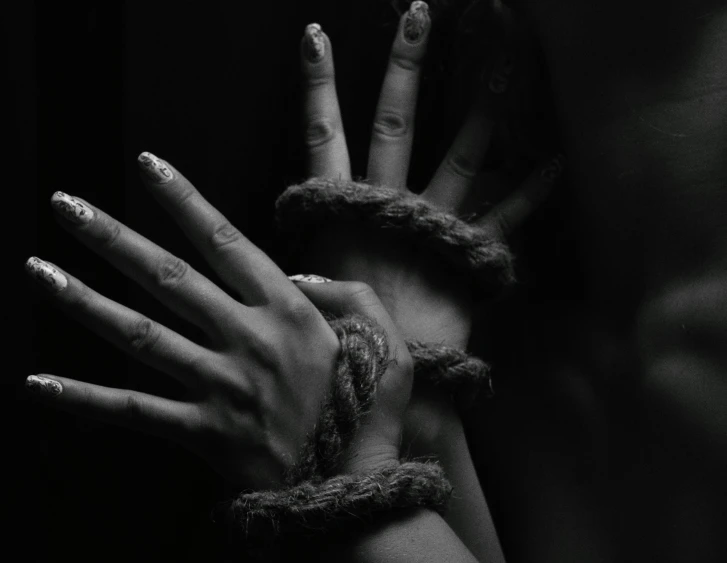 a black and white photo of a woman's hands wrapped in rope, a black and white photo, trending on pexels, renaissance, handcuffs, african domme mistress, painted nails, trapped in my conscious