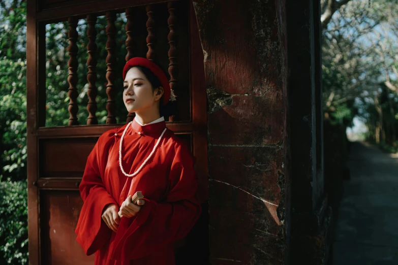 a woman in a red dress standing in front of a wooden door, inspired by Gu An, pexels contest winner, renaissance, ferred - themed robes and hat, vietnamese temple scene, girl wearing uniform, 15081959 21121991 01012000 4k