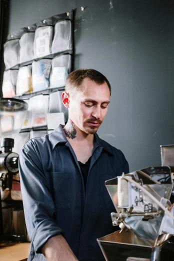 a man standing in front of a coffee machine, a portrait, inspired by Jakub Husnik, alchemist lab, profile image, tattooed, small manufacture