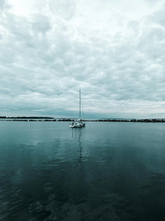 a sailboat floating on top of a large body of water, a picture, by Ryan Pancoast, pexels contest winner, grey cloudy skies, manly, bored ape yacht club, ultrawide angle cinematic view