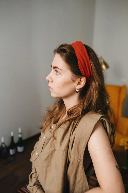 a woman with a red headband standing in a room, inspired by Josefina Tanganelli Plana, trending on pexels, side profile centered portrait, looking off into the distance, britt marling style, coral brown hair