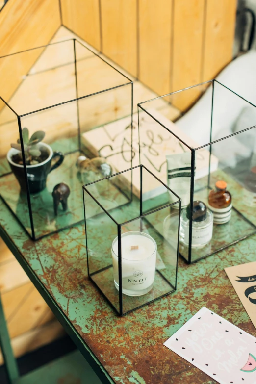 a couple of glass boxes sitting on top of a table, botanicals, holding a candle holder, on desk, angled