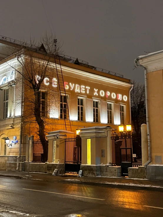 a very tall building sitting on the side of a road, overlaid with cyrillic words, warm street lights store front, neo classical architecture, 🚿🗝📝