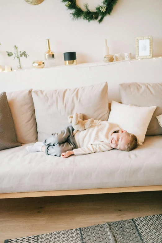 a baby laying on a couch in a living room, unsplash contest winner, minimalism, light beige pillows, full body hero, boys, low quality photo