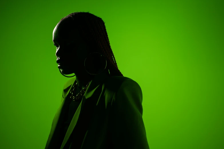 a woman standing in front of a green background, inspired by Elsa Bleda, trending on pexels, afrofuturism, dramatic soft shadow lighting, green concert light, adut akech, in front of a black background