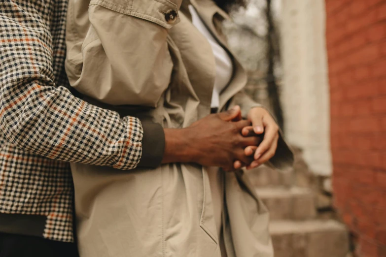 a man and woman holding hands in front of a brick building, trending on pexels, brown tuffle coat, african american, taupe, man grabbing a womans waist