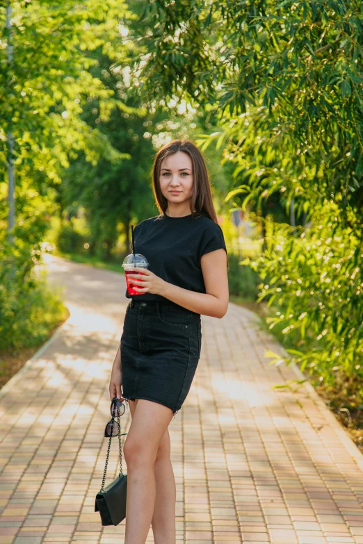 a woman in a black dress holding a cup of coffee, a picture, by Sven Erixson, shutterstock, walking at the park, russian girlfriend, 15081959 21121991 01012000 4k, teenager