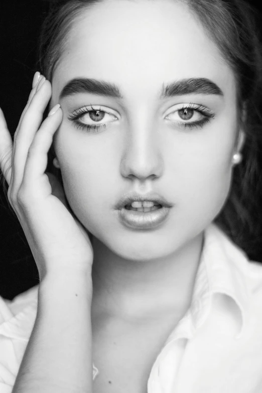 a black and white photo of a woman with her hands on her face, inspired by irakli nadar, tumblr, large eyebrows, 🤤 girl portrait, hyperrealistic teen, lilly collins