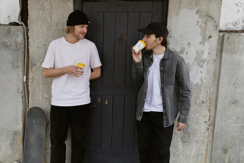 a couple of men standing next to each other, drinking a coffee, yellow cap, liam brazier, official store photo